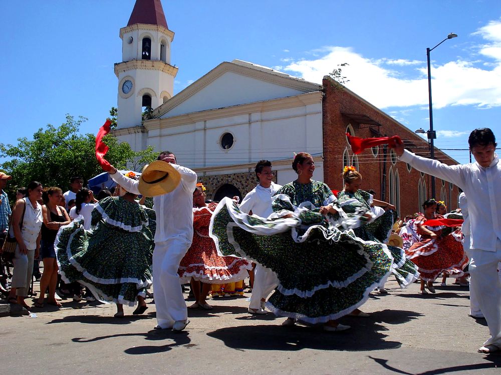 Couples dancing traditional Colombian folk dances in costume in front of the church in Melgar