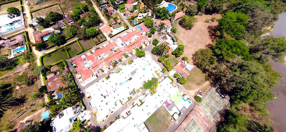 Vista aerea de un condominio residencial en Melgar rodeado de vegetacion y piscinas