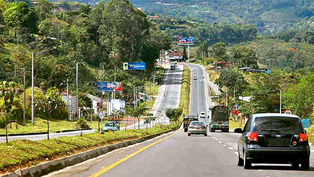 Vía de entrada a Melgar desde Bogotá, con carros y vegetacion tropical a lado y lado